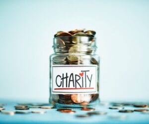 Image of a jar with money in - the jar has a label on that says 'charity'