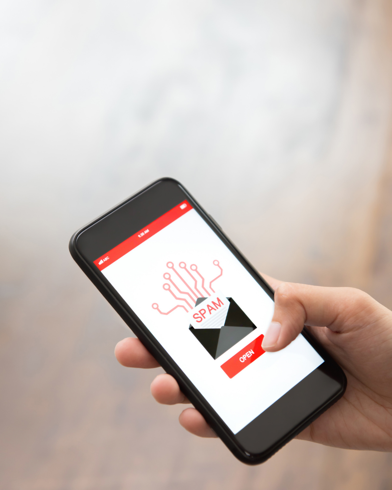 Image of a hand holding a phone. The phone has an email icon with the word SPAM underneath